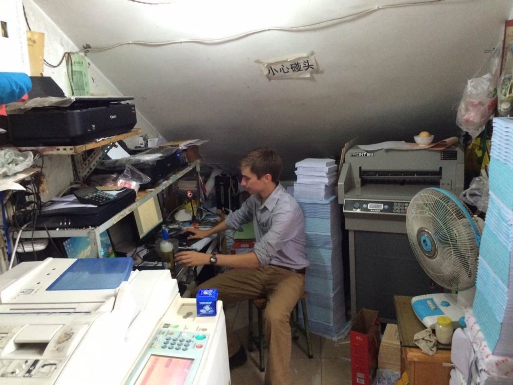 man sits at computer surrounded by stuff